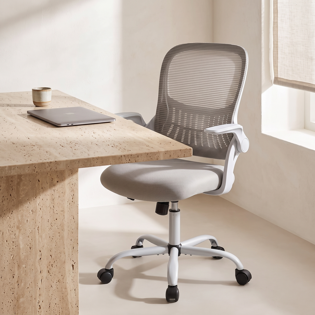 Chaise Ergonomique Essentiel — Gris — devant un bureau en travertin, lumière du matin